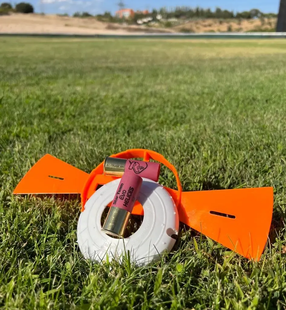 Gonzalo Gómez Arrimadas dando indicaciones técnicas a un alumno durante una clase de tiro deportivo en campo oficial, ambos con protección auditiva.