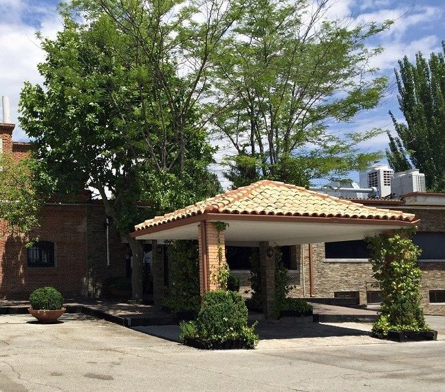 Gonzalo Gómez Arrimadas dando indicaciones técnicas a un alumno durante una clase de tiro deportivo en campo oficial, ambos con protección auditiva.